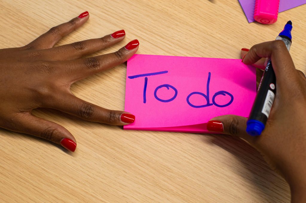 A person holding a pink sticky note and a marker