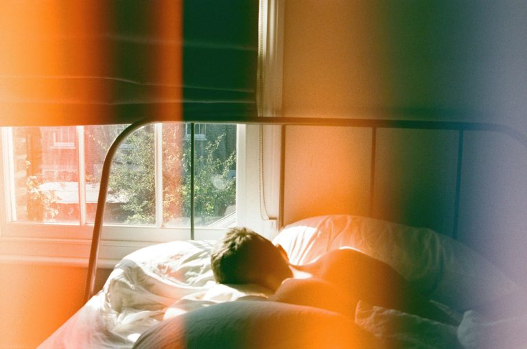 Person lying in bed beside window