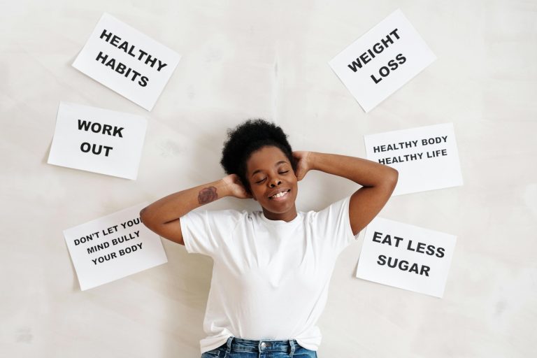 Woman in white crew neck shirt standing beside a wall with posted papers on healthy living