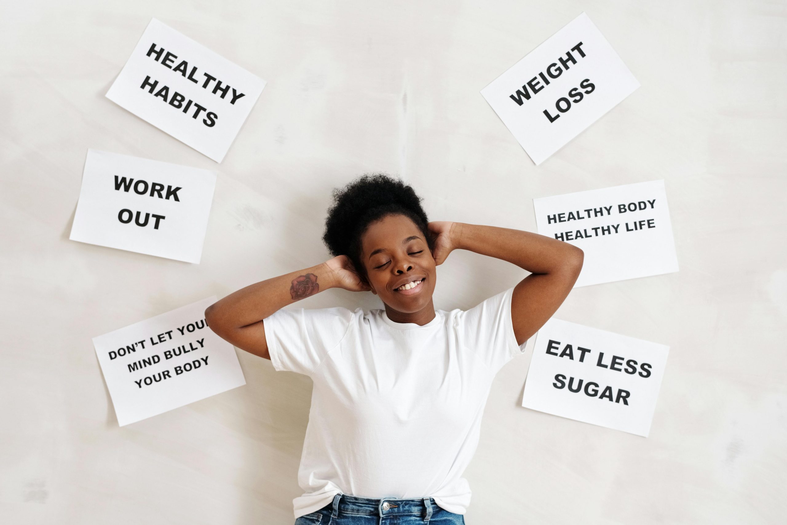 Woman in white crew neck shirt standing beside a wall with posted papers on healthy living